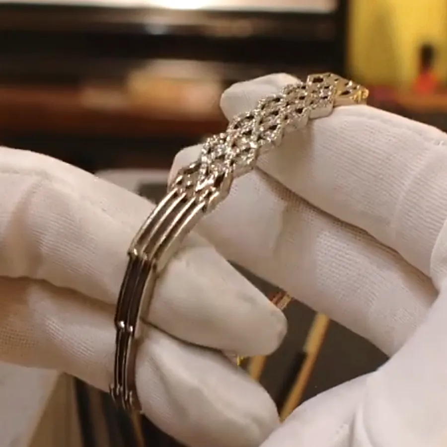 The same bracelet design in white gold, diamond-set lattice and handmade links, held in white gloves