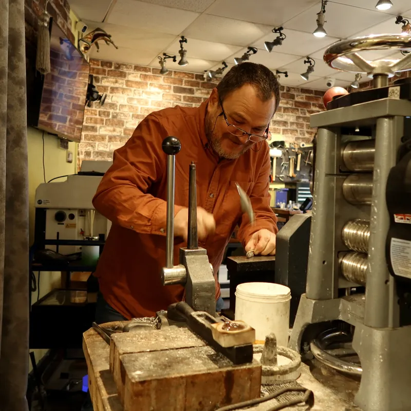 Colin hammering gold by hand beside the rolling mill