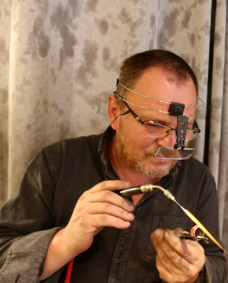Colin at the bench, soldering a ring with a fine torch