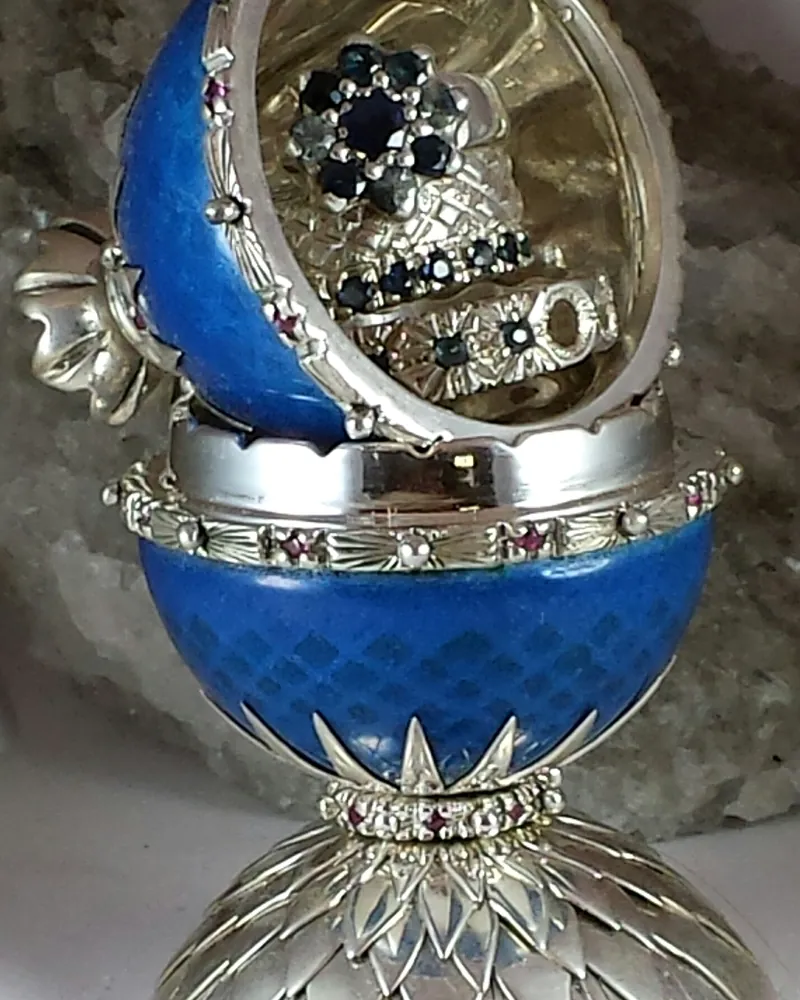 Blue enamel egg standing open, with two gem-set rings inside